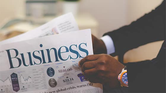 a close up view of a man wearing a black suit and a watch holding a newspaper with the word "business" on the cover; image used for a blog post about five tax breaks from the new tax law
