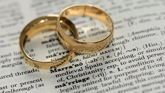 two golden rings representing marriage sitting on top of a dictionary page; image used for blog post about spousal ira