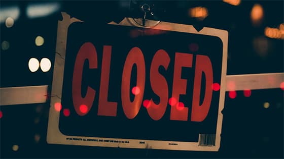 a sign sitting behind a window with the red words "closed," image used for blog post about business closing during COVID-19 pandemic