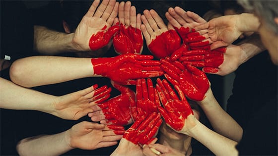 a collective of hands come together with red paint forming a heart; image used for blog post about retaining not-for-profit members