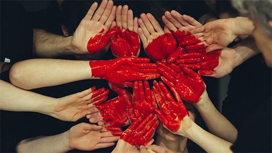 a collective of hands come together with red paint forming a heart; image used for blog post about charitable deduction substantiation
