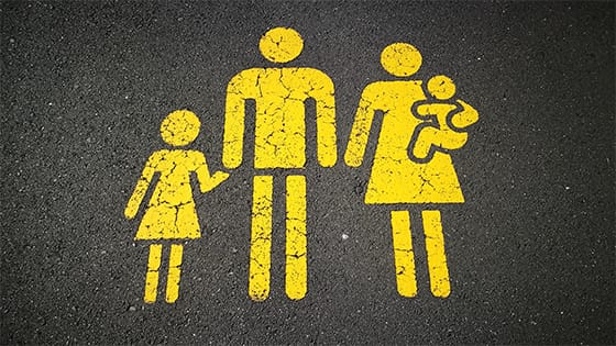grey asphalt with figures drawn in yellow, depicting a family of parents with a small child and baby; image used for blog post about qualifying for head of household tax filing status