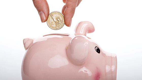 A person dropping a coin into a piggy bank; image used for blog post about tax options to build up a college fund