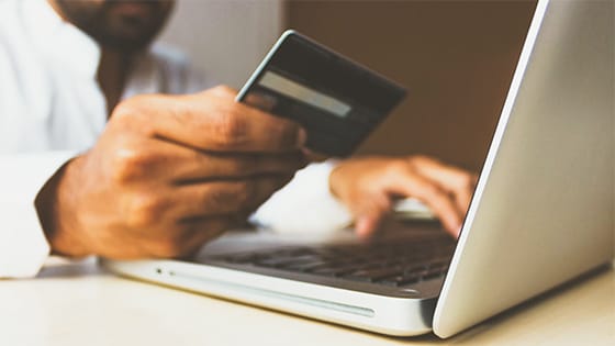 person holding a credit card and looking at a laptop; image used for blog post about deductibility of corporate expenses