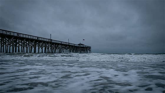 a pier on a stormy cloudy day with rough waves in the water; image used for blog post about casualty loss tax deduction