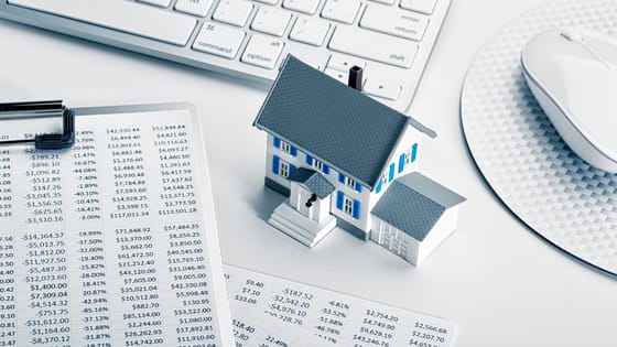 An image of a tiny model home sitting next to a keyboard and documents with numbers; image used for blog post about homeowners deducting seller-paid points