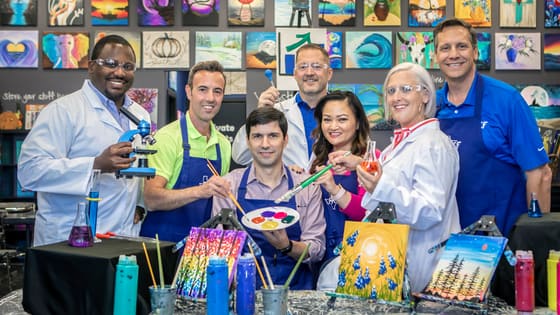 A photo of PKF Texas team members posing with art and science props for a market brand refresh