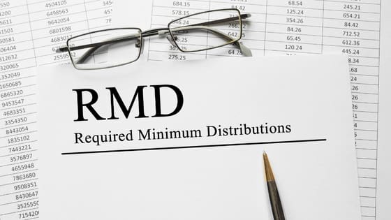A photo of reading glasses and a pen sitting on top of a document saying, "RMD Required Minimum Distributions;" image used for blog post about 7 things to know about IRA withdrawals