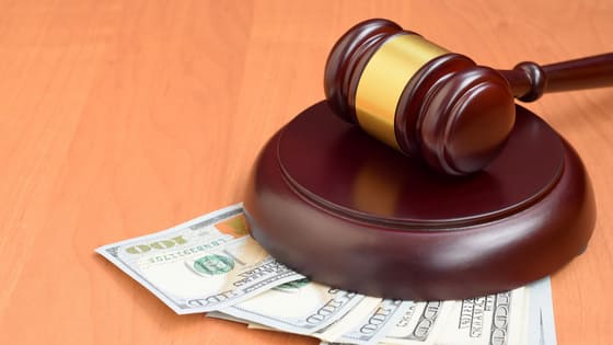 An image of a gavel sitting on top of hundred dollar bills; for blog post about tax exceptions for lawsuit settlement money