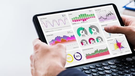A photo of someone holding a tablet with graphs and data analytics