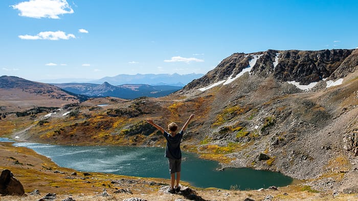 Young boy standing on a hillside overlooking a lake below | fulltime families