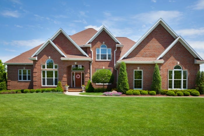 Beautiful brick home surrounded by a lush, healthy green lawn under a clear blue sky