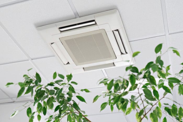 ceiling-mounted cassette air conditioning unit installed in a grid-style ceiling