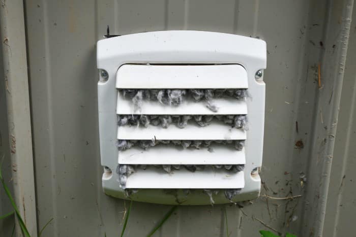 Exterior dryer vent blocked by lint, indicating urgent professional cleaning