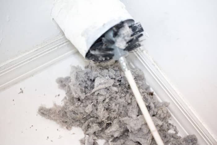 Brush tool cleaning a dryer vent with a large amount of lint removed and gathered on the floor