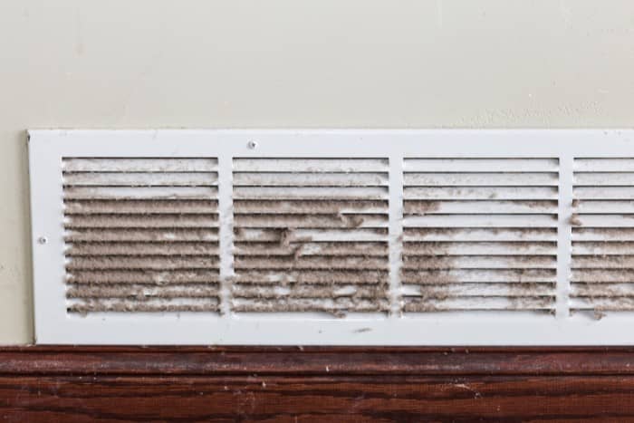 a wall-mounted air vent covered in dust and debris