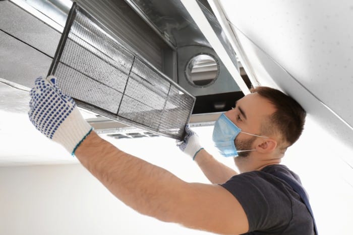 a male technician performing maintenance on an HVAC system