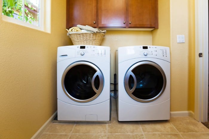 Laundry room with side-by-side washing machine and dryer beneath wooden storage cabinets