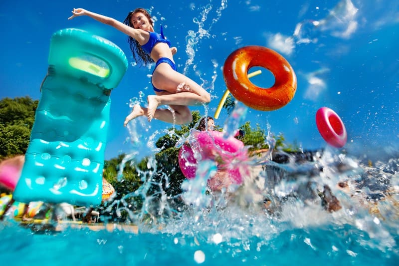 girl jumping into the pool with floats
