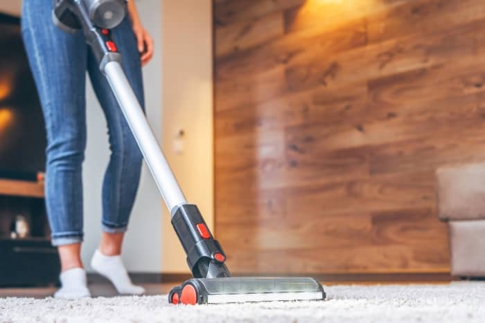 Woman Cleaning the Carpet with Cordless Vacuum Cleaner
